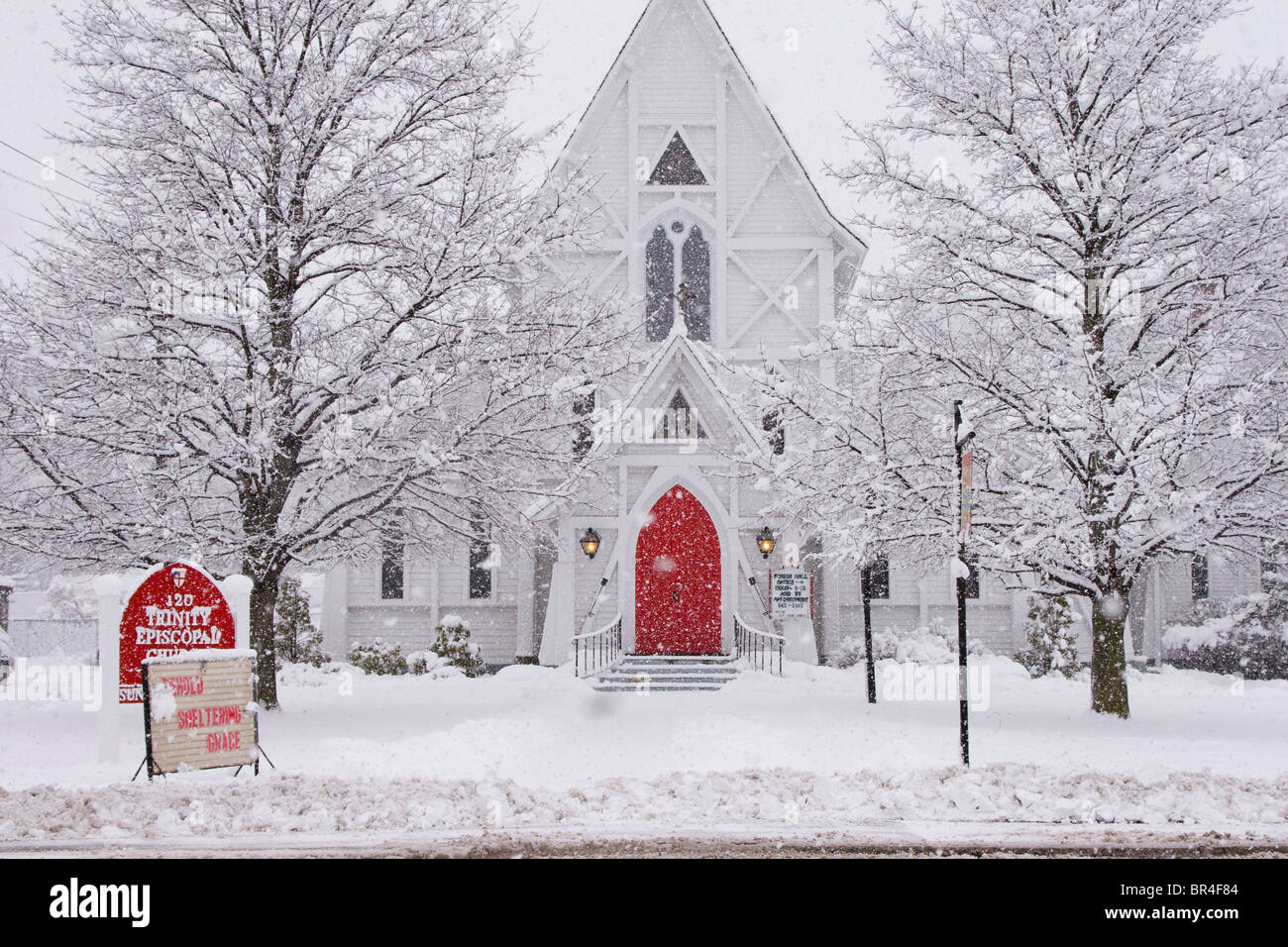 Chiesa bianca con porta rossa in inverno tempesta di neve Foto Stock