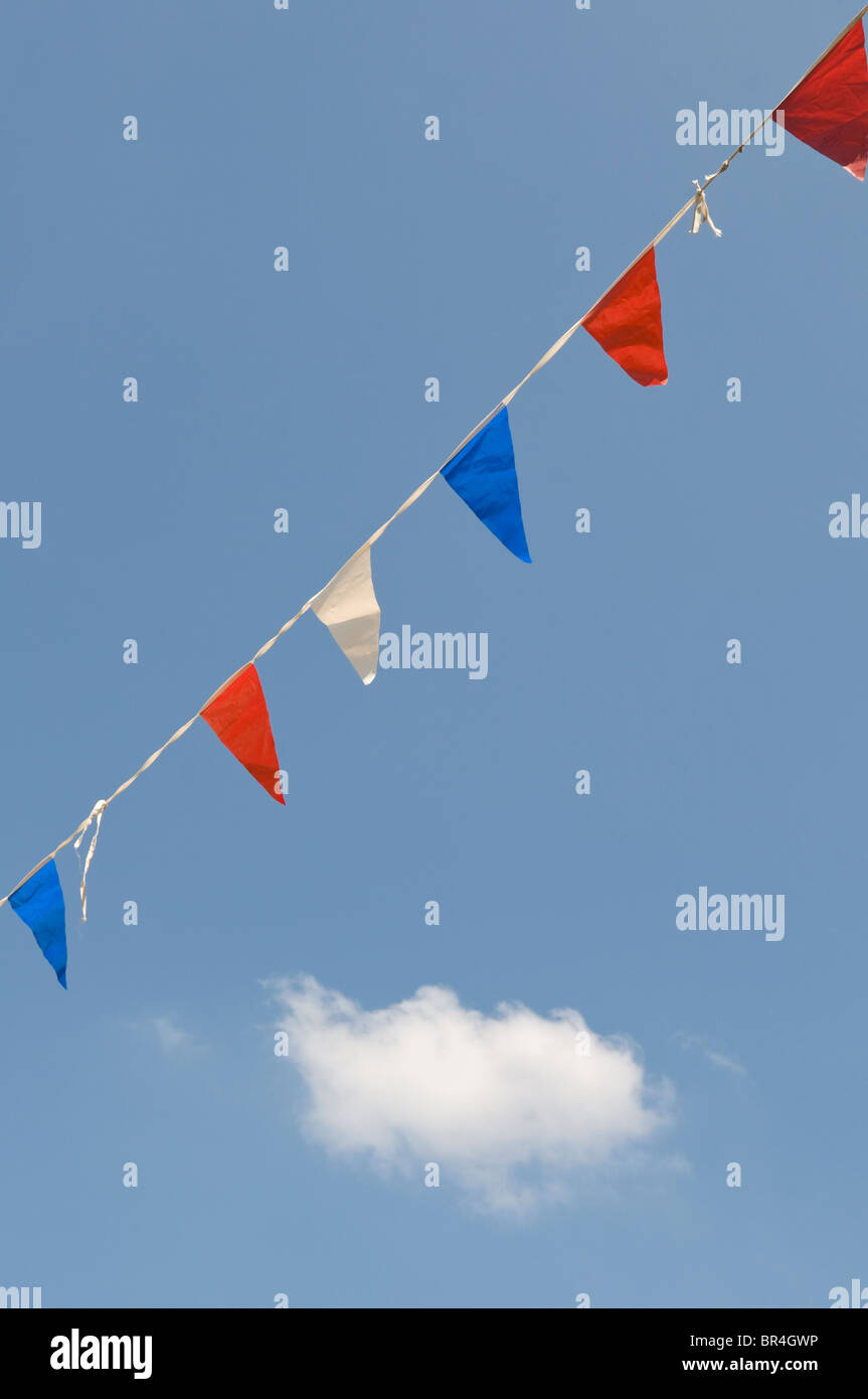 Rosso, bianco e blu bunting in un cielo blu con una singola nuvola bianca. Foto Stock