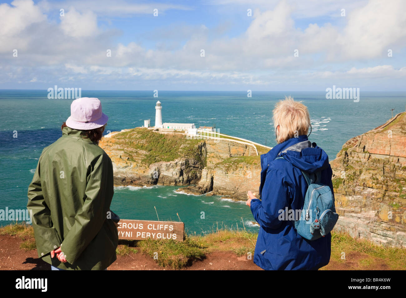 Sud Stack, Isola di Anglesey, Galles del Nord, Regno Unito. Due donne turisti sulla cima delle scogliere guardando la vista al faro Foto Stock
