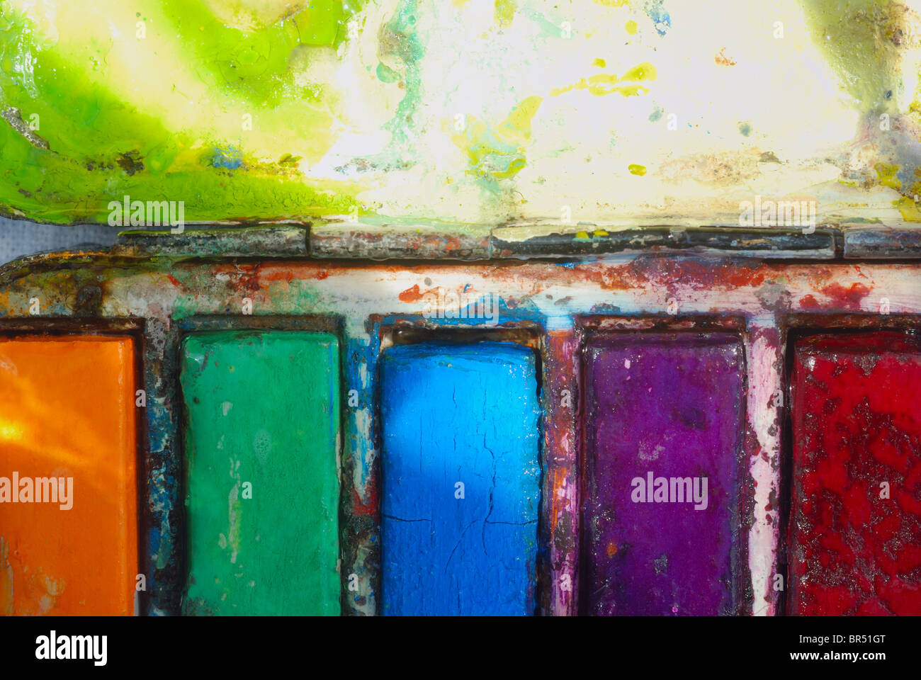 Dell'artista usato vintage acquerello paintbox, grande vicino sul arancione, verde, blu, viola e la vernice rossa e blocchi di palette di miscelazione. Foto Stock