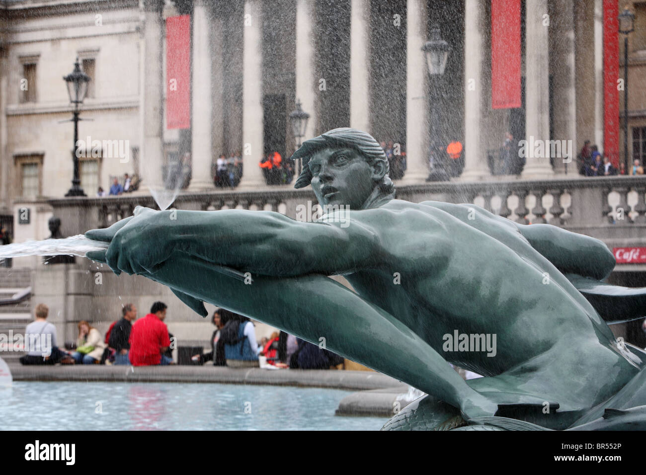 Giovane uomo con la fontana dei Delfini su Trafalgar Square, Westminster, Londra, WC2. Foto Stock