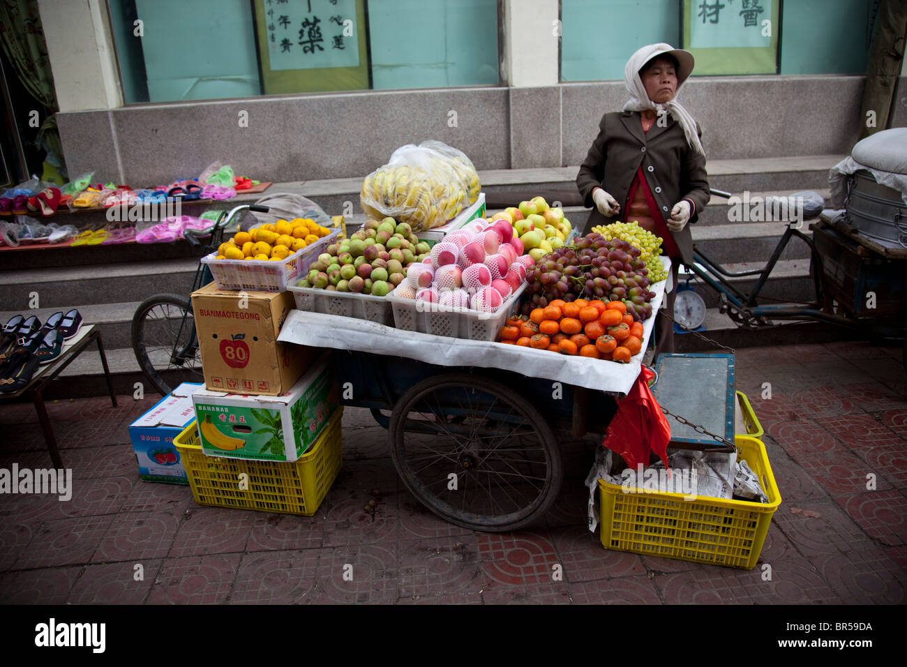 Donna Senior per la vendita di frutta da moto in Jiayuguan Gansu in Cina. Foto Stock