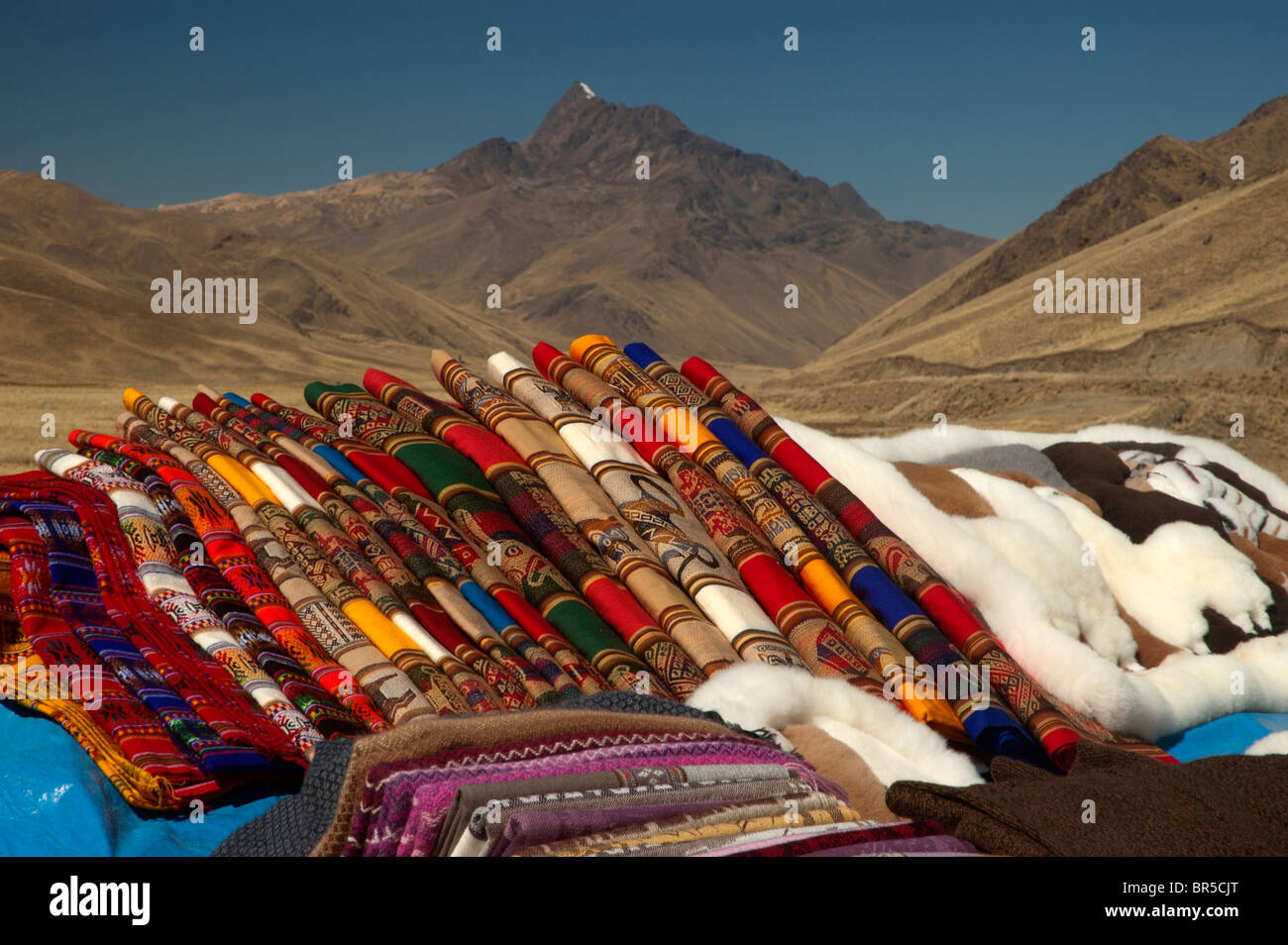 Tessuti colorati e vestiti per la vendita presso la stazione di La Raya Pass, la quota massima sulla strada da Cusco a Puno, Perù. Foto Stock