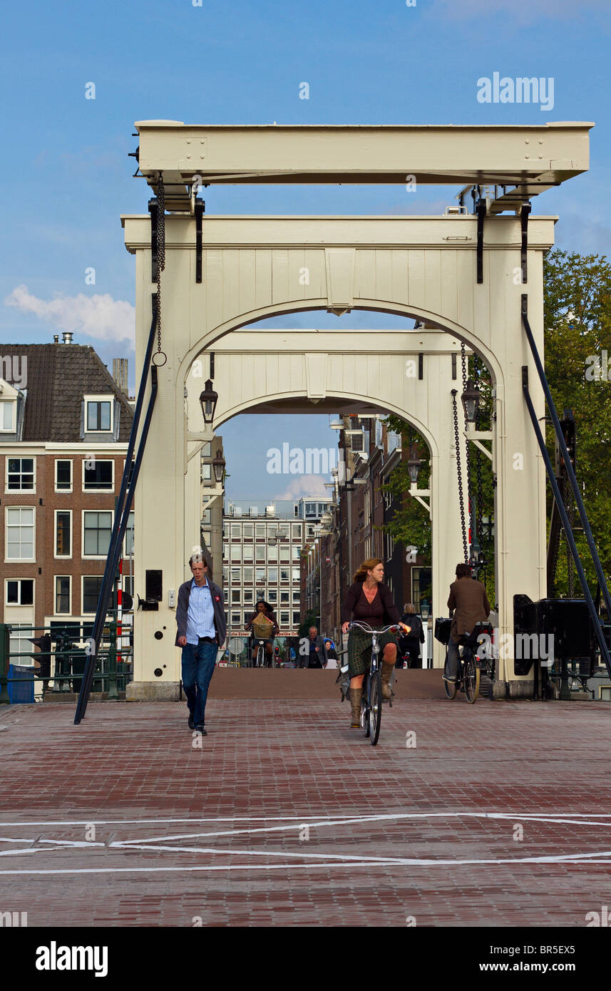 I ciclisti attraversando ponte sul fiume Amstel di Amsterdam, Olanda Foto Stock