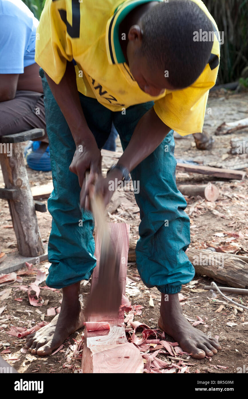 Nungwi, Zanzibar, Tanzania. Dhow Costruzione, Boat Building. Smussatura di una nervatura usando un adze. Foto Stock