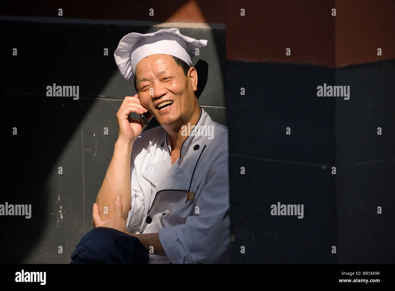 Cuocere i colloqui sul telefono cellulare, Shanghai, Cina Foto Stock