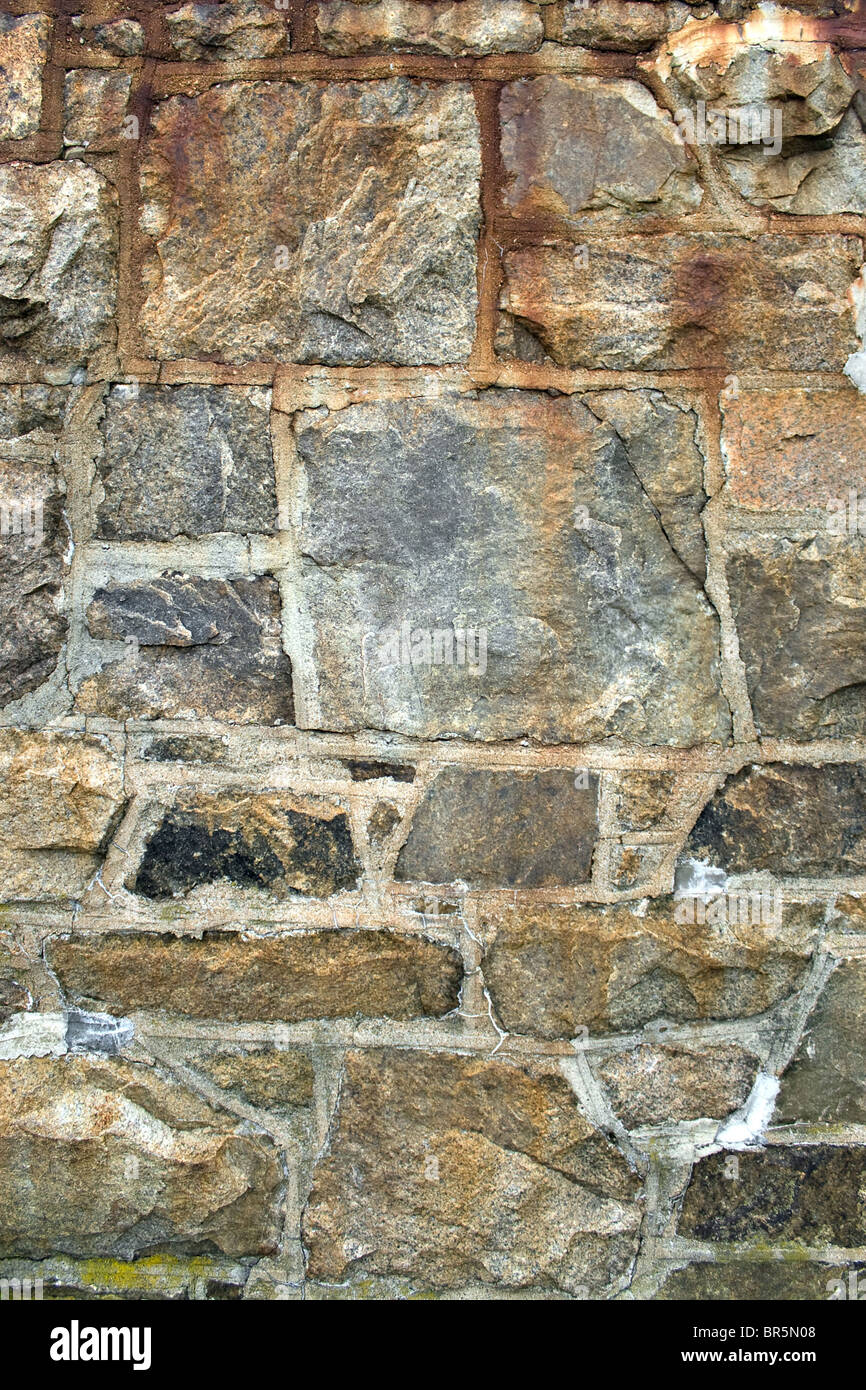 Un antico muro di pietra tessitura che è alterata e coperto con un po' di luce moss. Foto Stock