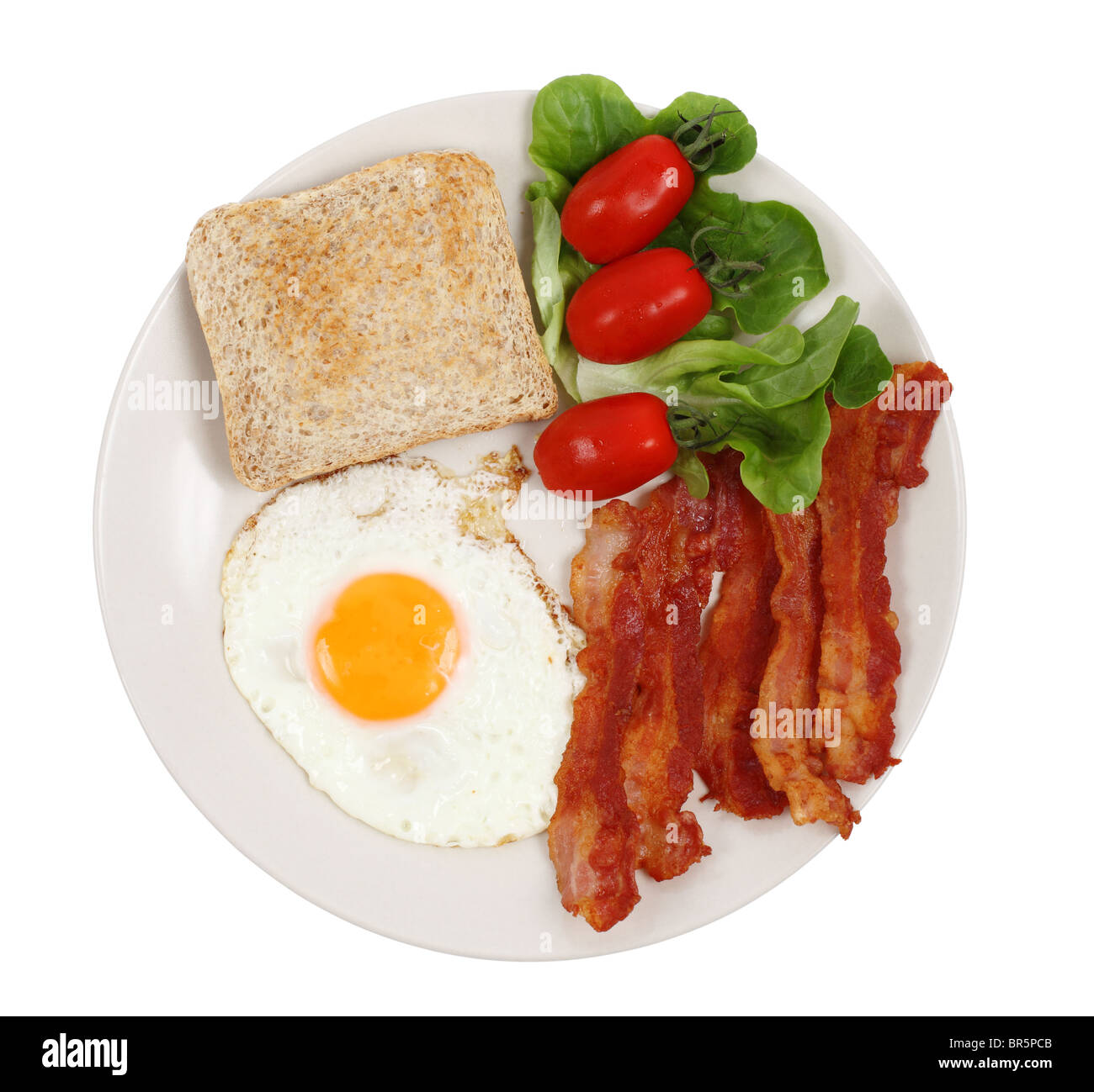 La prima colazione la piastra con uova, bacon, pane tostato e pomodori isolate su sfondo bianco Foto Stock