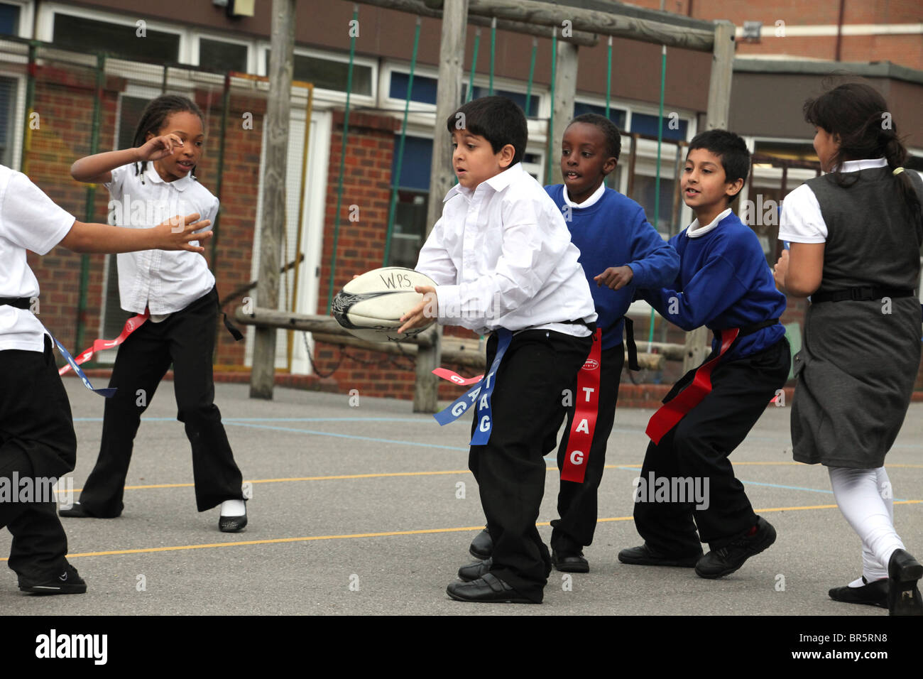 La scuola dei bambini giocare a rugby tag flag o il rugby. Sono dieci anni dall'anno 6. Foto Stock