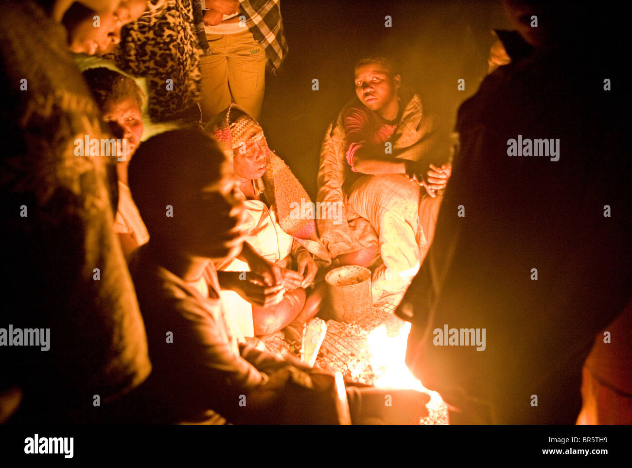 Un gruppo di gente di strada si raccolgono intorno ad un fuoco a uno di loro "basi" su una terra desolata di Harare, Zimbabwe. Foto Stock