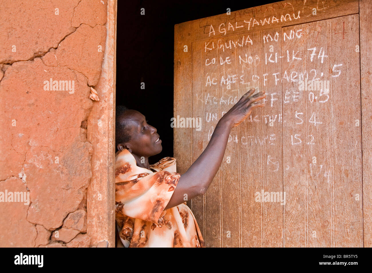 Monica Kigwa mantiene un record delle sue aziende di produzione sulla porta della sua casa. Monica è affetti da malaria. Uganda. Foto Stock