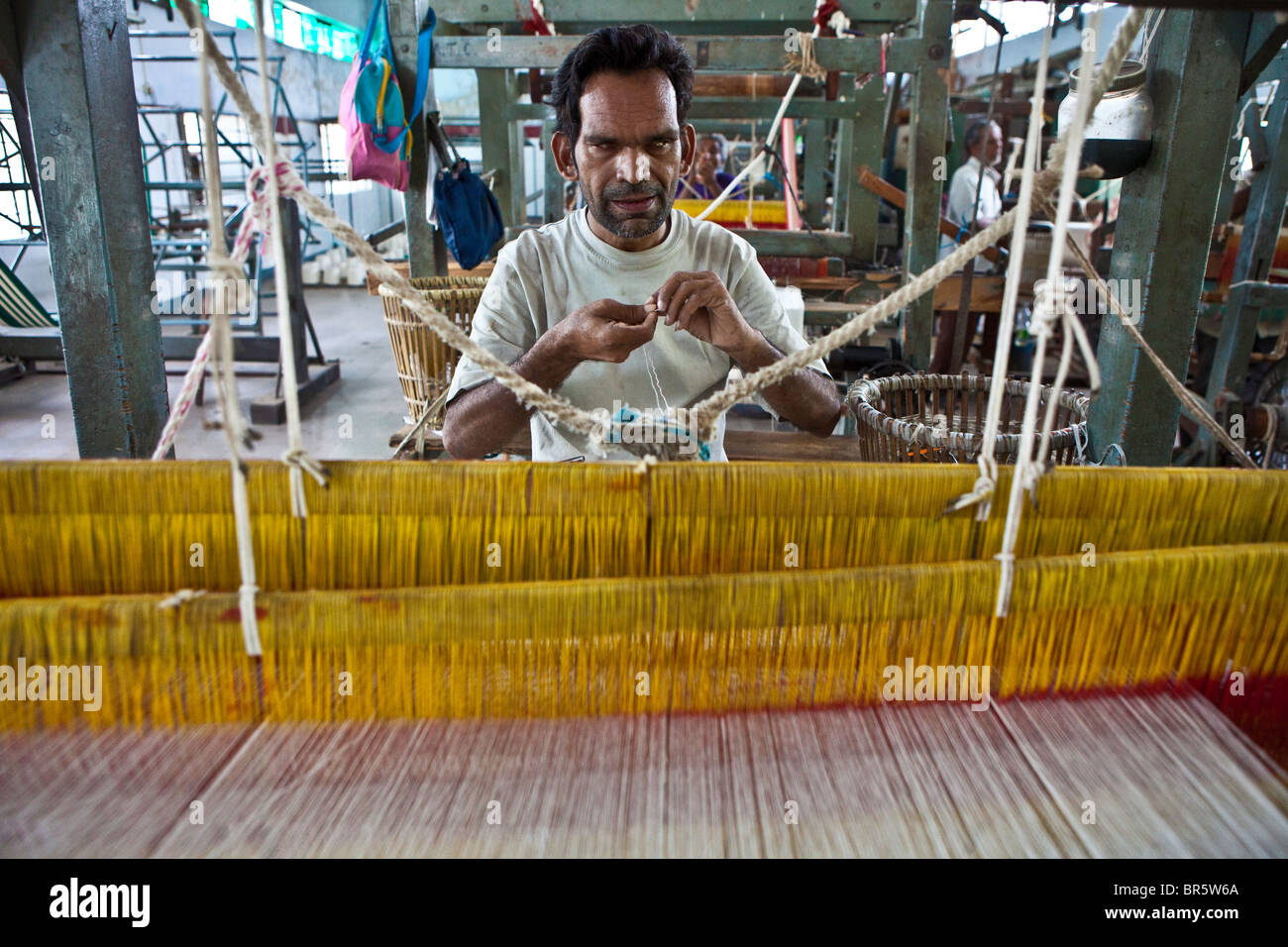 Un uomo cieco utilizzando un telaio di tessitura presso il centro di formazione delle persone non vedenti Association (Andhjan Mandal), Ahmedabad. India. Foto Stock