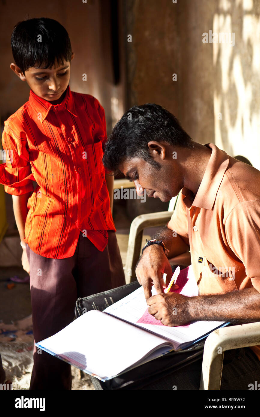 Govrind, un dodicenne ragazzo depositi alcuni dei suoi soldi in banca di risparmio e Balgar, Madhiya Road, Kumbharwada, India. Foto Stock