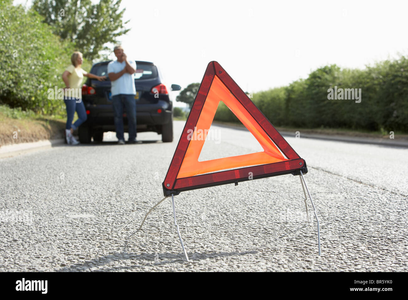 Giovane ripartiti sulla strada di campagna con luci di avvertimento segno in primo piano Foto Stock