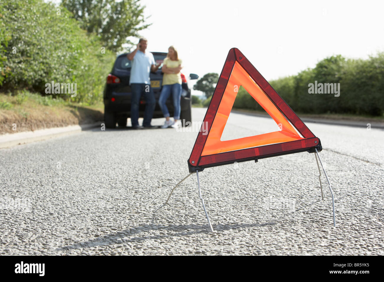 Giovane ripartiti sulla strada di campagna con luci di avvertimento segno in primo piano Foto Stock