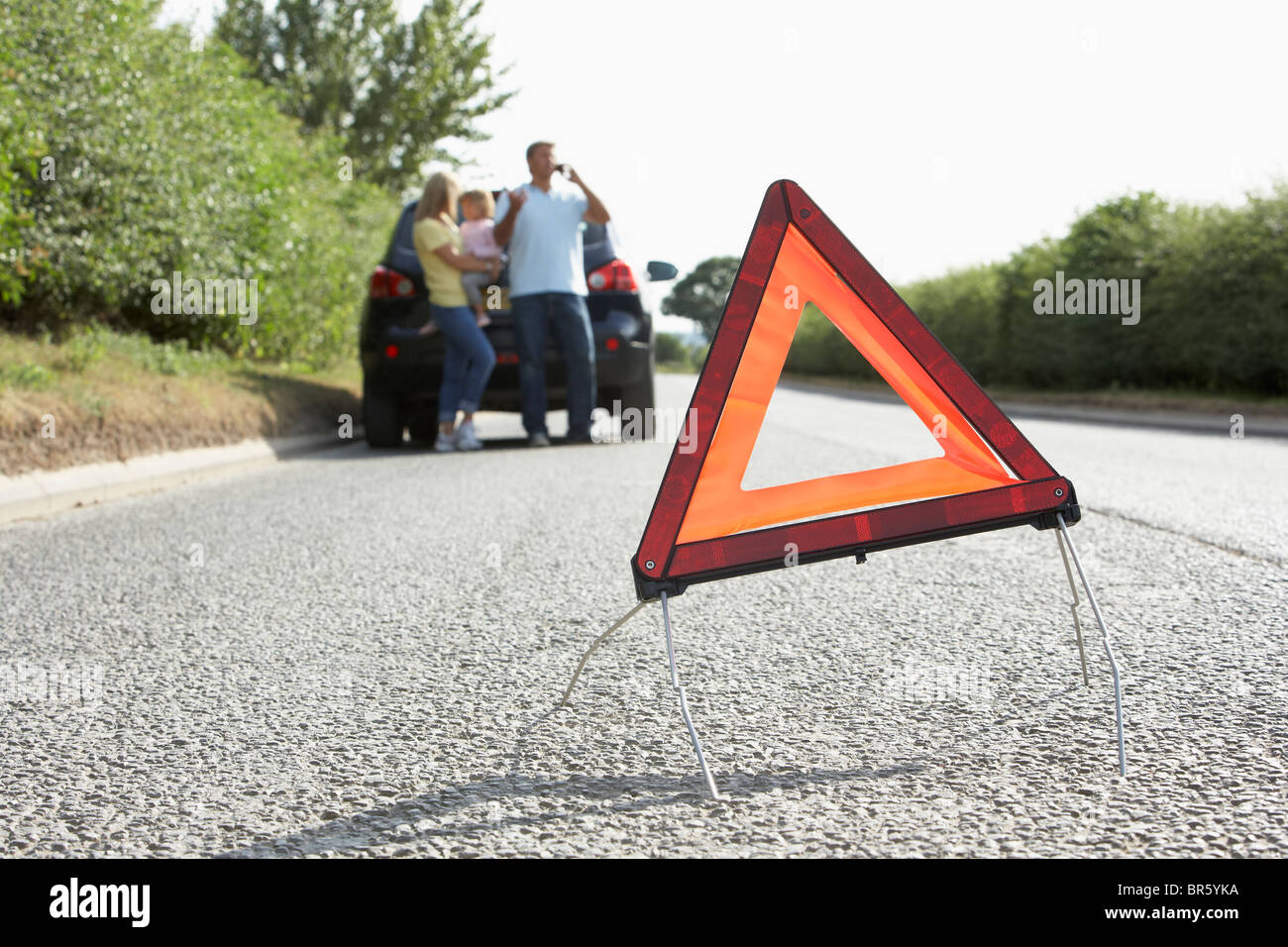 Famiglia ripartiti sulla strada di campagna con luci di avvertimento segno in primo piano Foto Stock