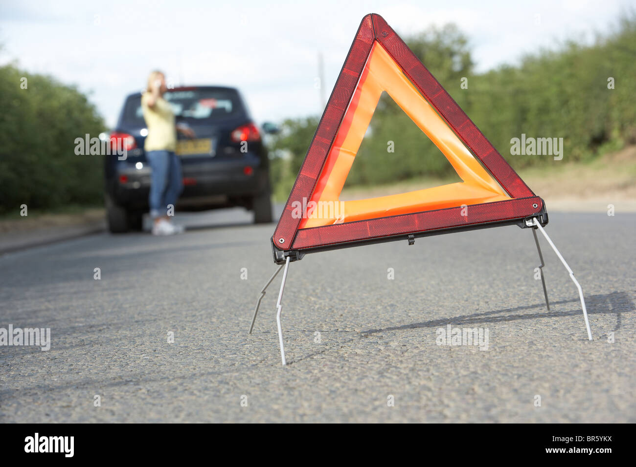 Driver femmina ripartiti sulla strada di campagna con luci di avvertimento segno in primo piano Foto Stock