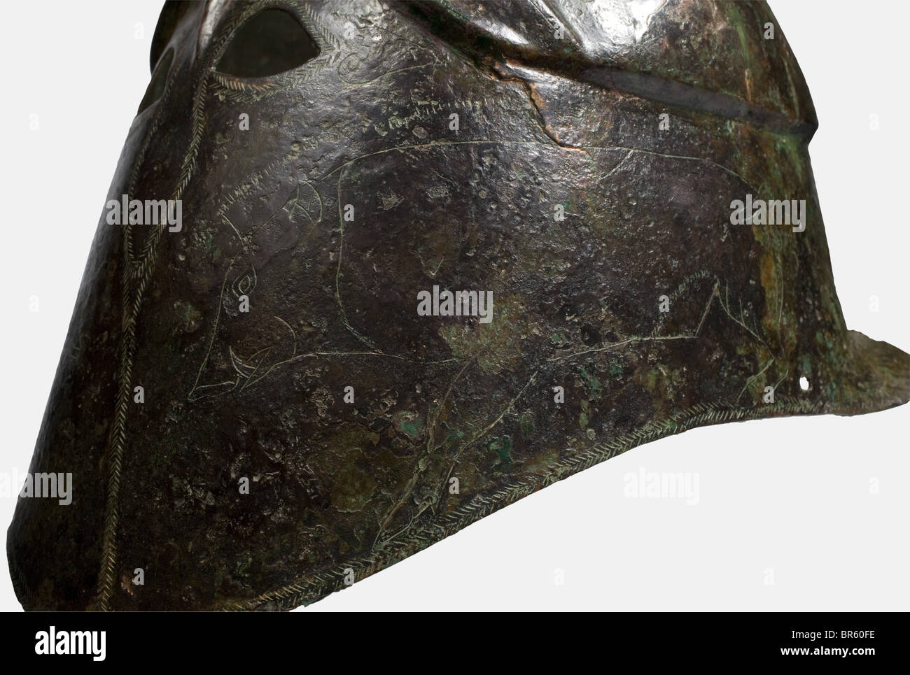 Un casco apuliano-corinzio, 5th secolo a.C. bronzo, alto casco con calotta sfalsata e sopracciglia distintamente contornate. Piccole aperture per gli occhi con incisione del bordo che si estende verso il basso per indicare la protezione per il naso e la linea di separazione per le guance. Raffigurazioni incise di cinghiali sulle guance. Una forcella del pennacchio rivettata alla corona. Due fori per le sottogola ai lati del bordo inferiore. Altezza 22,5 cm. Peso 630 g. Patina verde-marrone. Solo i resti della protezione del collo sono stati conservati. Il lato destro è leggermente spinto verso l'interno e rotto, Foto Stock