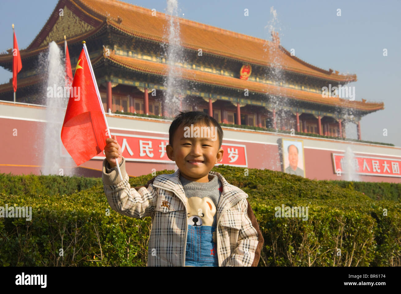 Ragazzo holding bandiera nazionale di fronte a Piazza Tien An Men Tower, Pechino, Cina Foto Stock