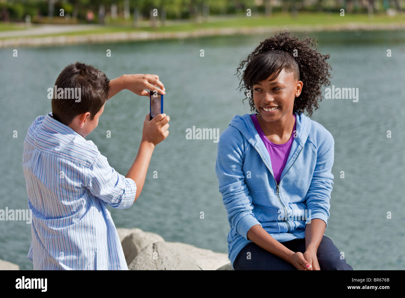 Culturale multiculturale ragazzo adolescente utilizzando iPhone cellulare tenendo immagine fotografia teen ragazza. diversità razziale Foto Stock