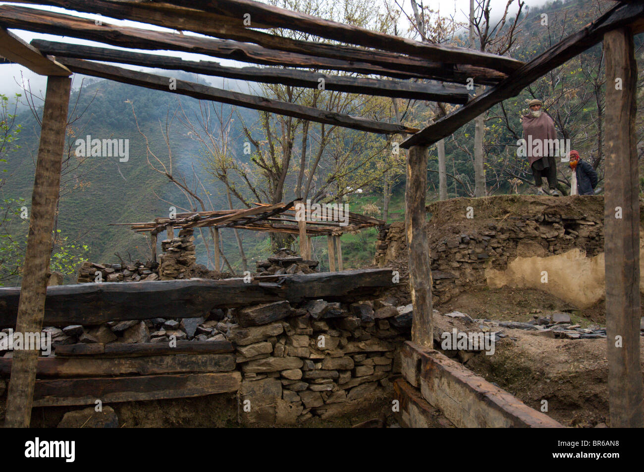 Una famiglia Pashtun sondaggi le rovine della loro casa di montagna distrutta dal terremoto e l'inizio della ricostruzione-t Foto Stock