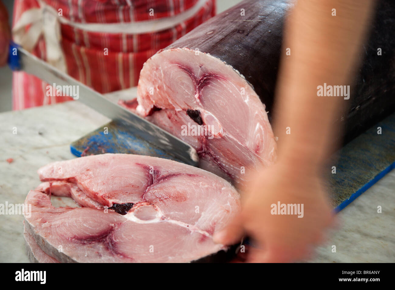 Un pescivendolo il taglio delle bistecche di pesce spada in un pescivendolo in Malta. Foto Stock