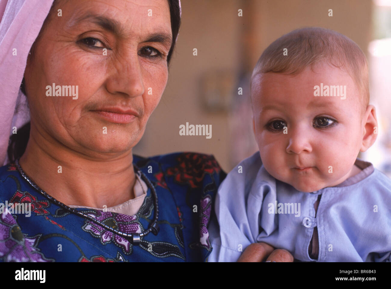 Una donna tagiko detiene un bambino con kohl gli occhi cerchiati in una casa famiglia di Mazar-i-Sharif esitano Provincia Foto Stock