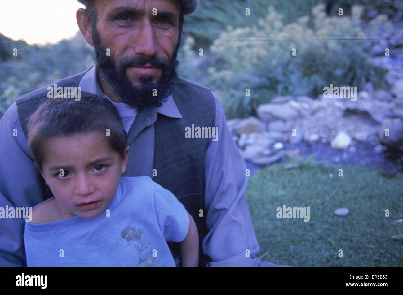 Un uomo tagiko e suo figlio rilassarsi in un campo del Panjshir Valley Hindu Kush e montagne. Foto Stock