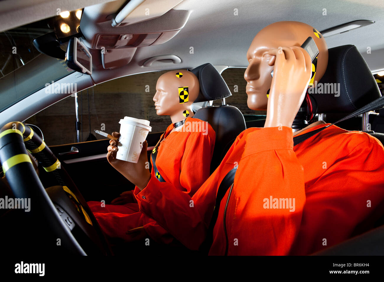 Un crash test dummy incautamente utilizzando un telefono cellulare durante la guida con un crash test passeggeri fittizia Foto Stock