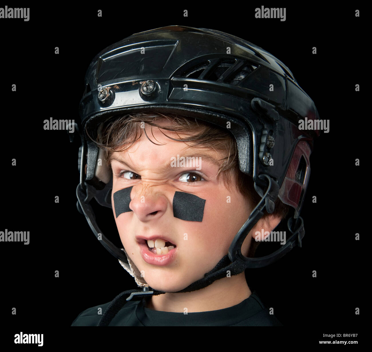 Un giovane giocatore di hockey indossando headware protettivo snarls presso la fotocamera Foto Stock