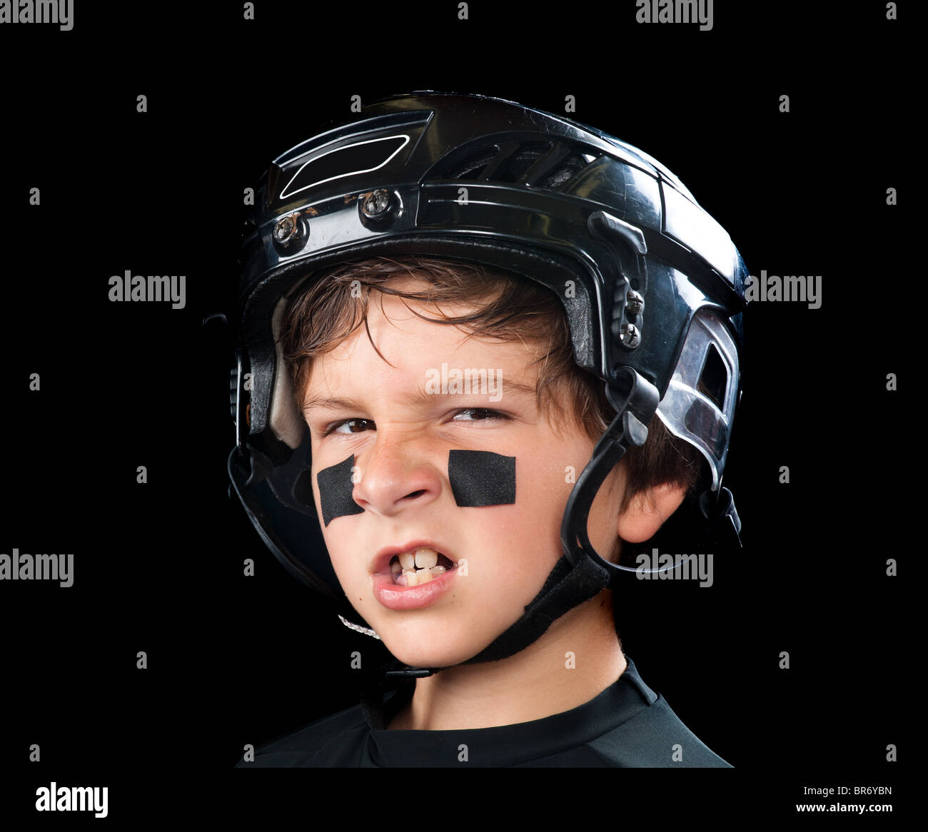 Un giovane giocatore di hockey indossando headware protettivo snarls presso la fotocamera Foto Stock