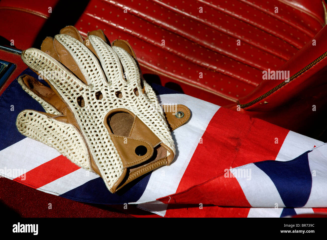 Guanti da guida in pelle retro stringback tradizionali, sedili in pelle rossa di UNA British Sports Car e British UK Union Jack Flag Folded Still Life Foto Stock