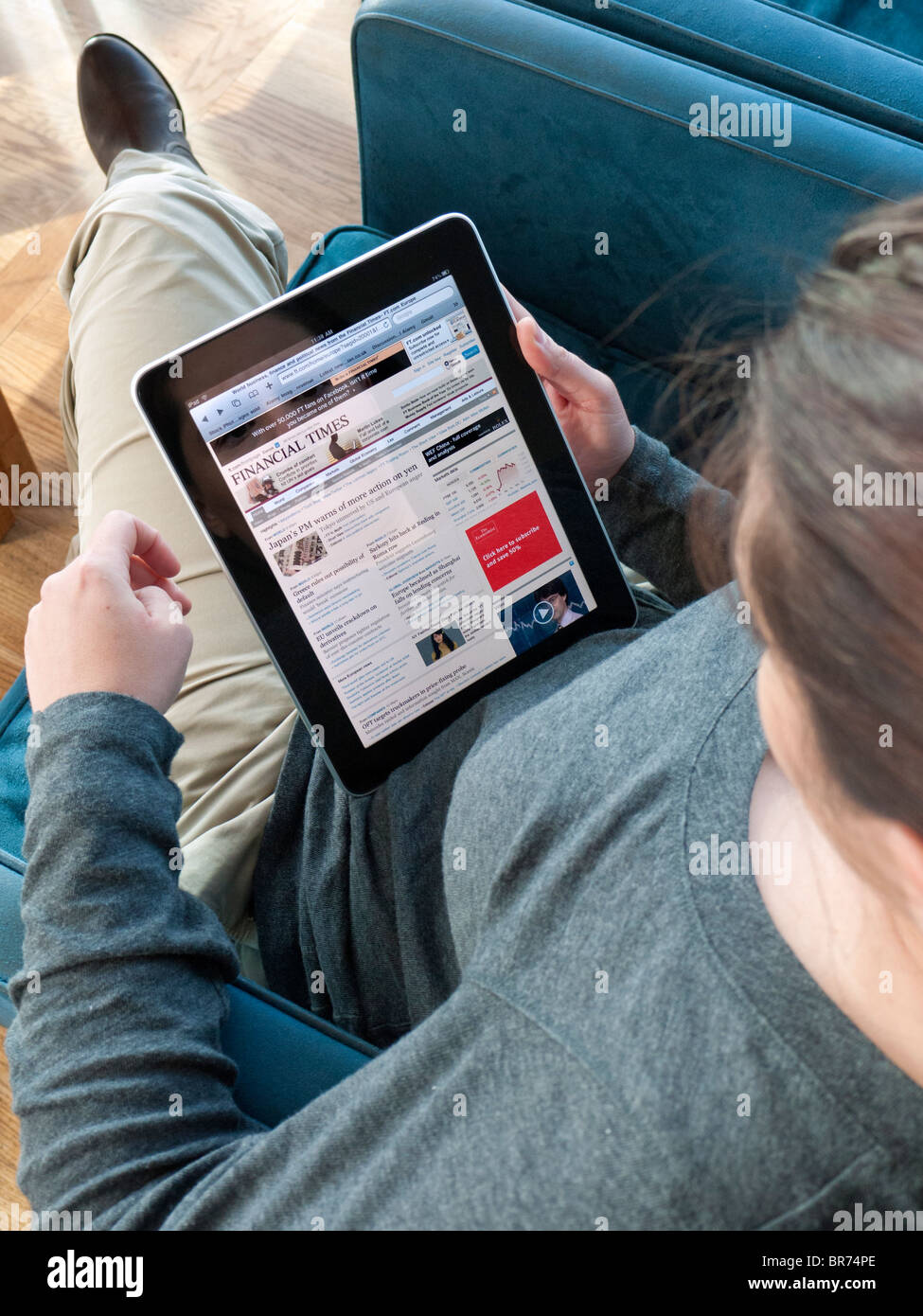 Donna che utilizza iPad tavolo per computer in airport lounge di partenza e la lettura Financial Times online giornale aziendale Foto Stock