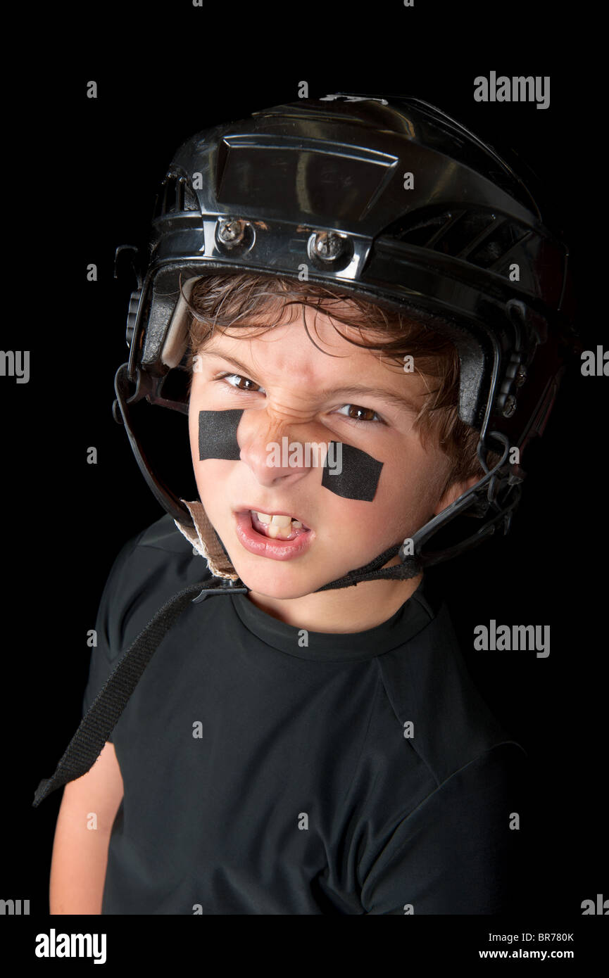 Una gioventù sudate giocatore di hockey che indossa il suo casco di sicurezza snarls alla fotocamera. Foto Stock