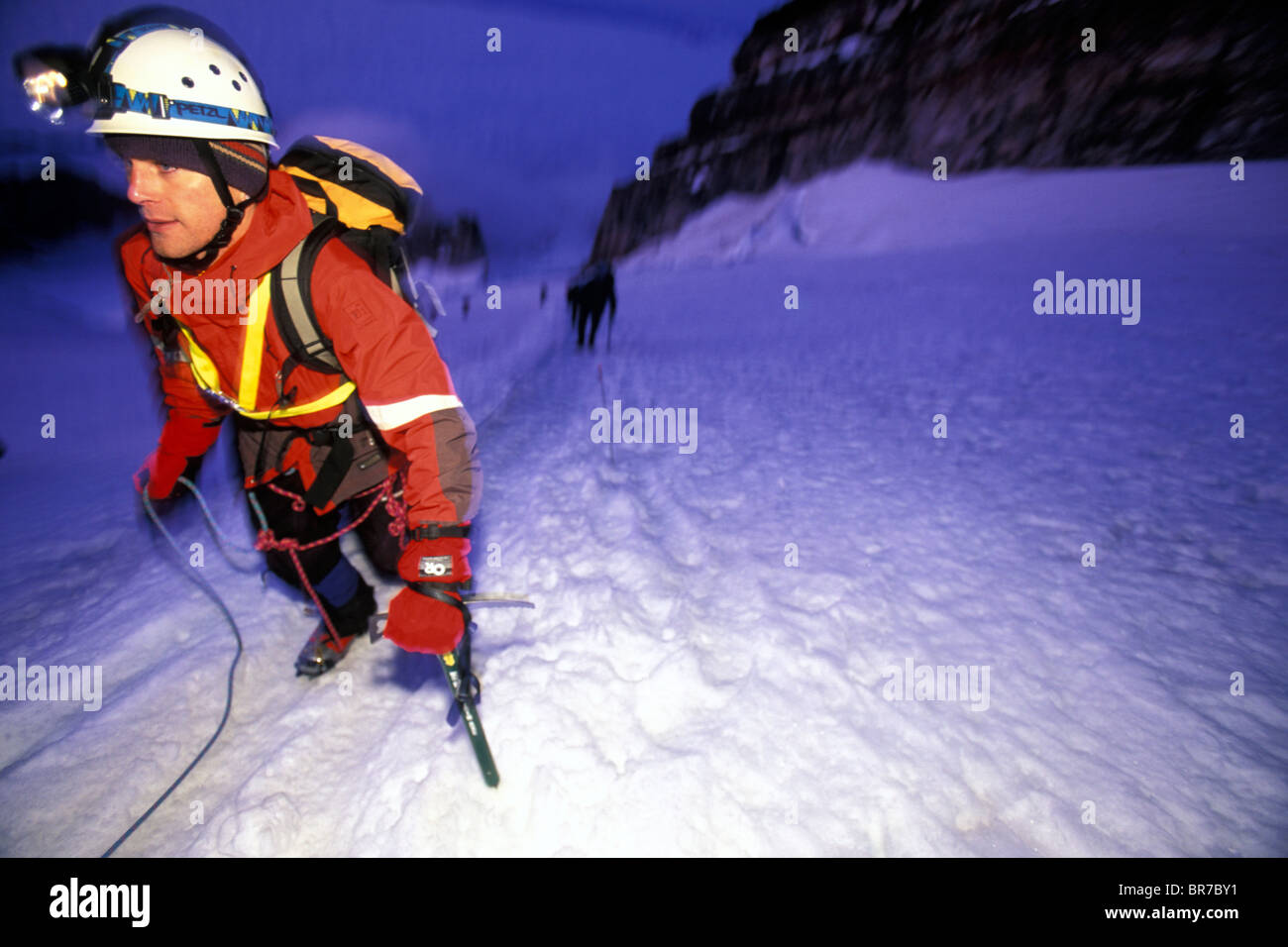 Scalatore con il team dietro di lui summiting Mount Rainier Washington in condizioni di luce scarsa. Foto Stock