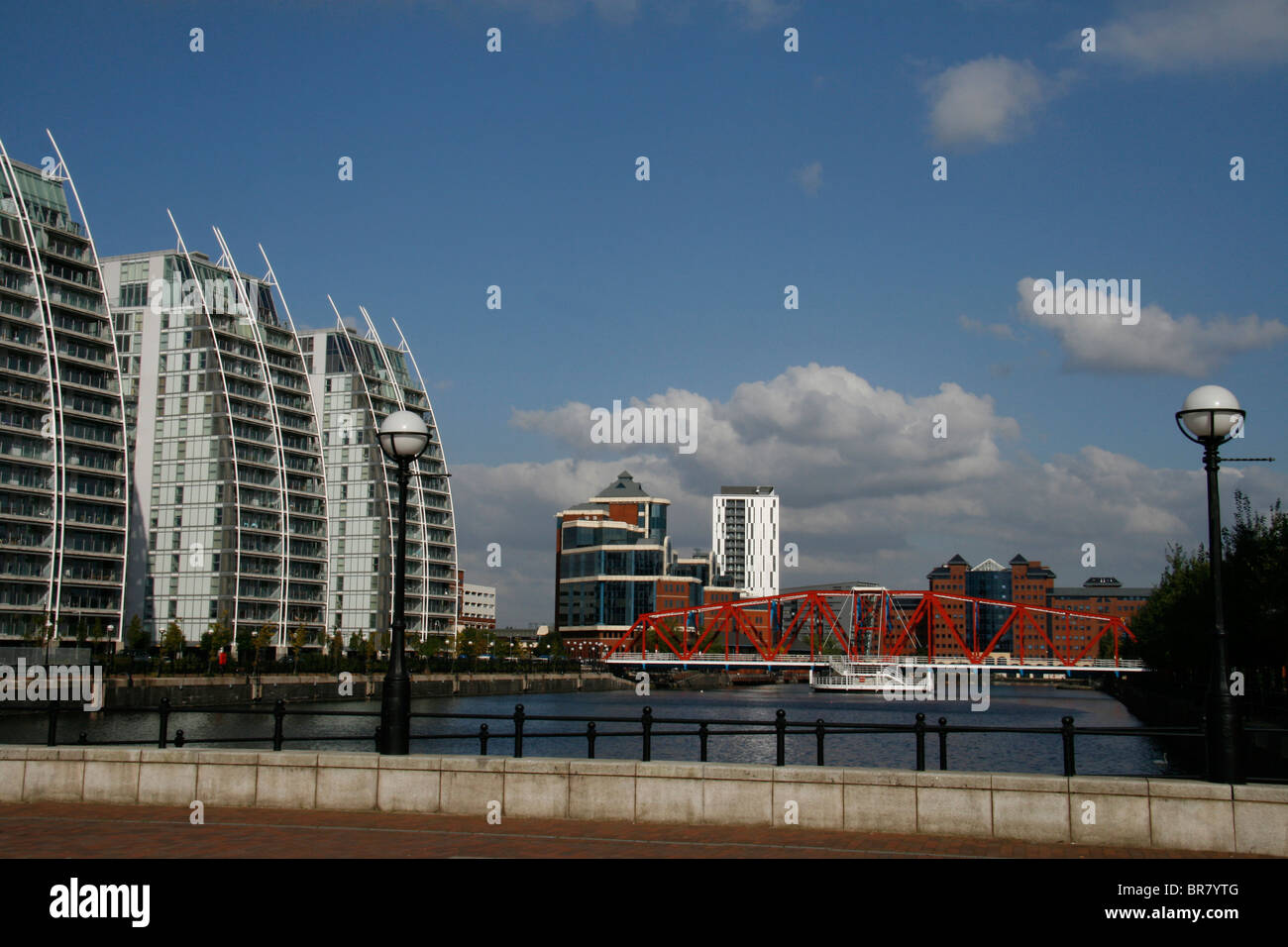 Vista di moderni edifici per uffici e appartamenti a Salford Quays, Manchester, Inghilterra con ponte rosso in primo piano. Foto Stock