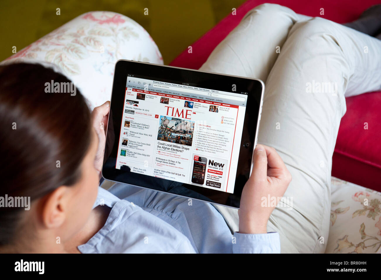 Donna che utilizza computer tablet iPad per leggere il tempo magazine online Foto Stock