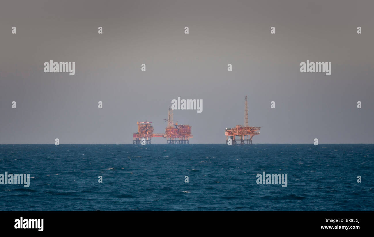 Mare del Nord impianti di trivellazione del petrolio illuminata da un sole di setting Foto Stock