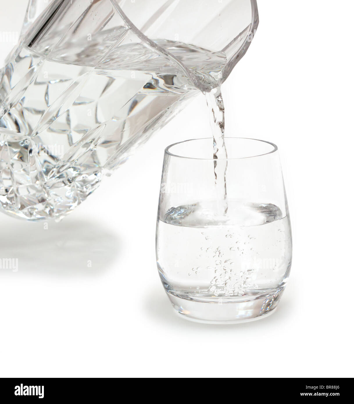 Versando un bicchiere di acqua fresca da una caraffa di cristallo Foto Stock