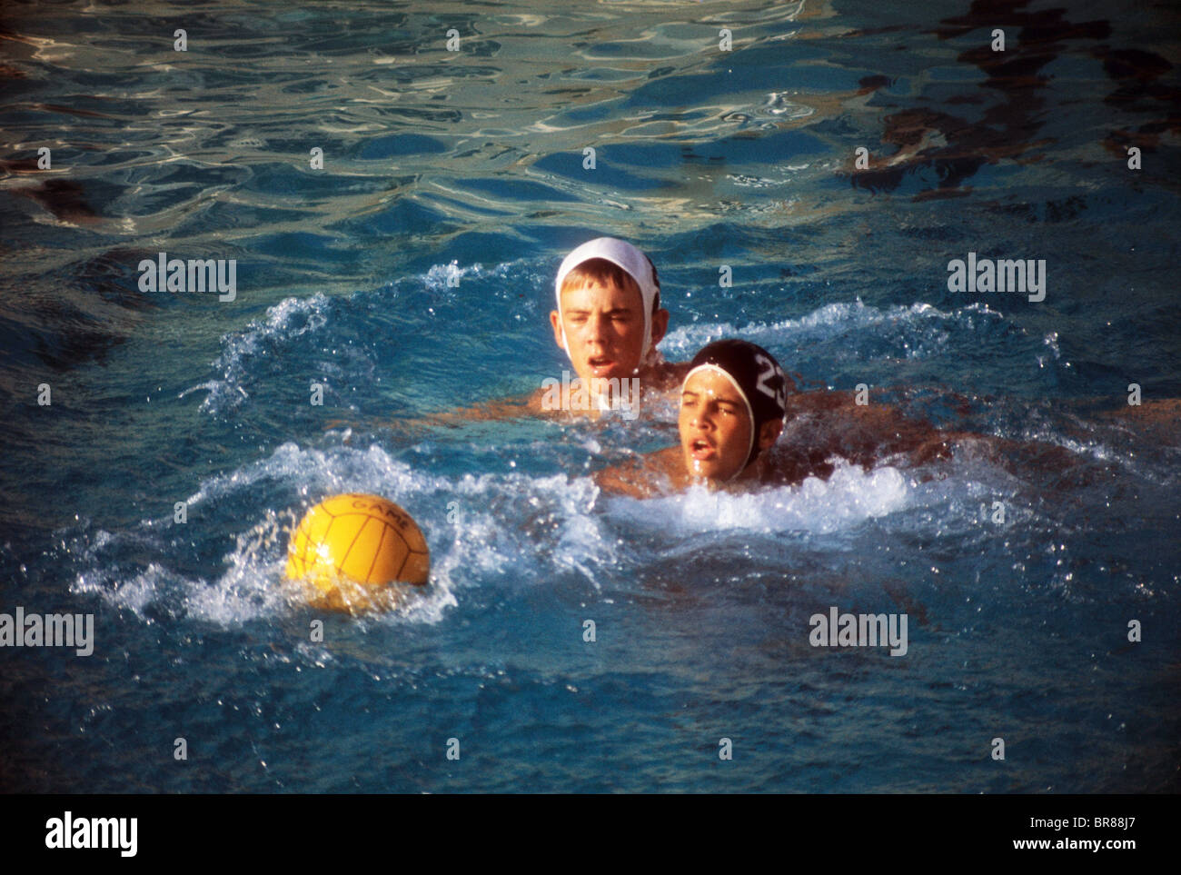 Teen boy giocare a pallanuoto palla nuotare in piscina evitare escape specialità Foto Stock