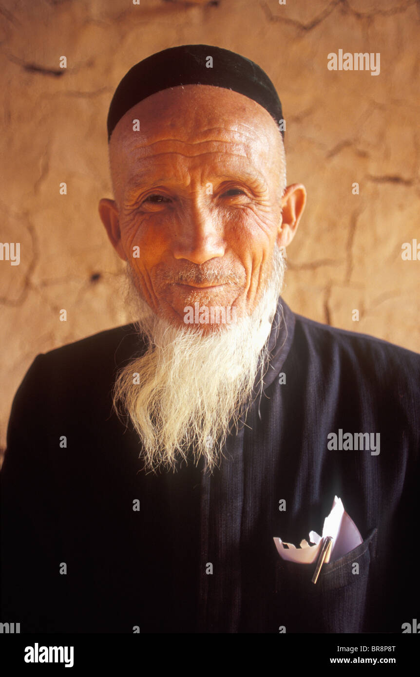 Un anziano uomo Uighur pone per un ritratto in remoto villaggio di Tuyoq Cina. Foto Stock