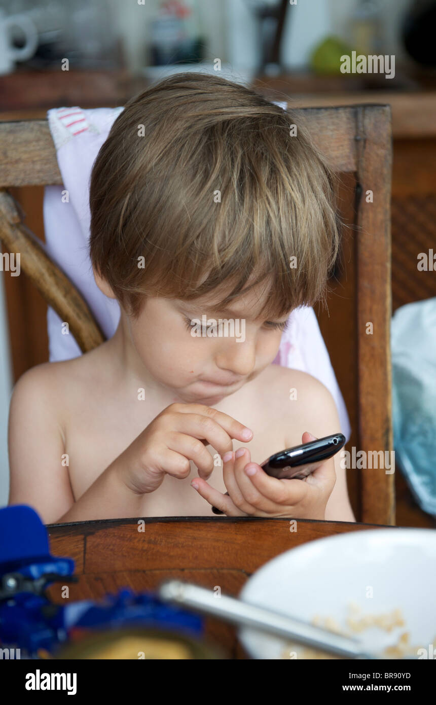 Ragazzo giovane la riproduzione di ben 10 gioco su un iphone in Ibiza, SPAGNA Foto Stock