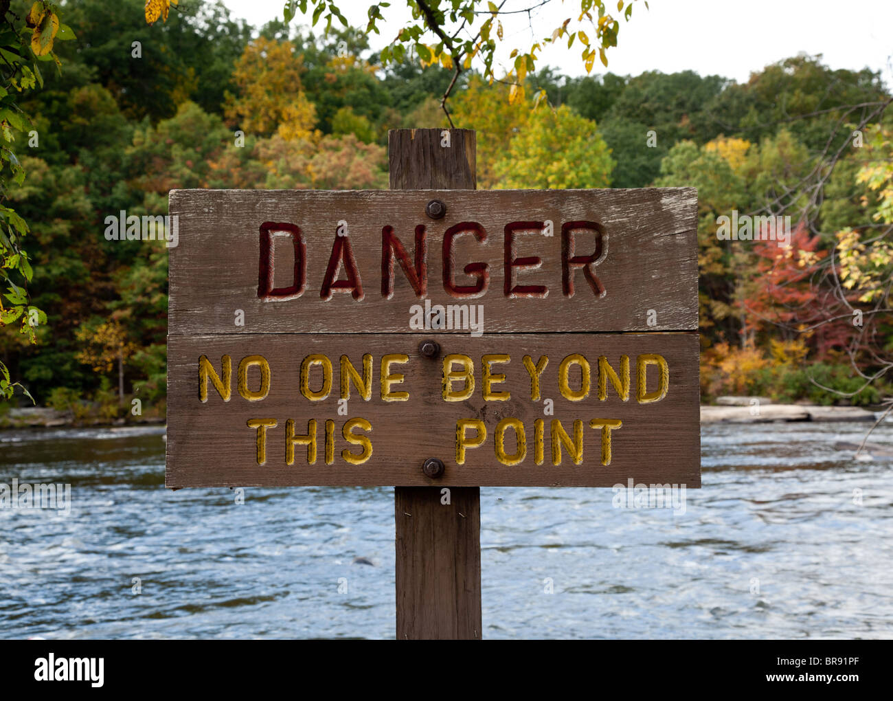 In legno pitturato segno di pericolo dal fiume impetuoso Foto Stock