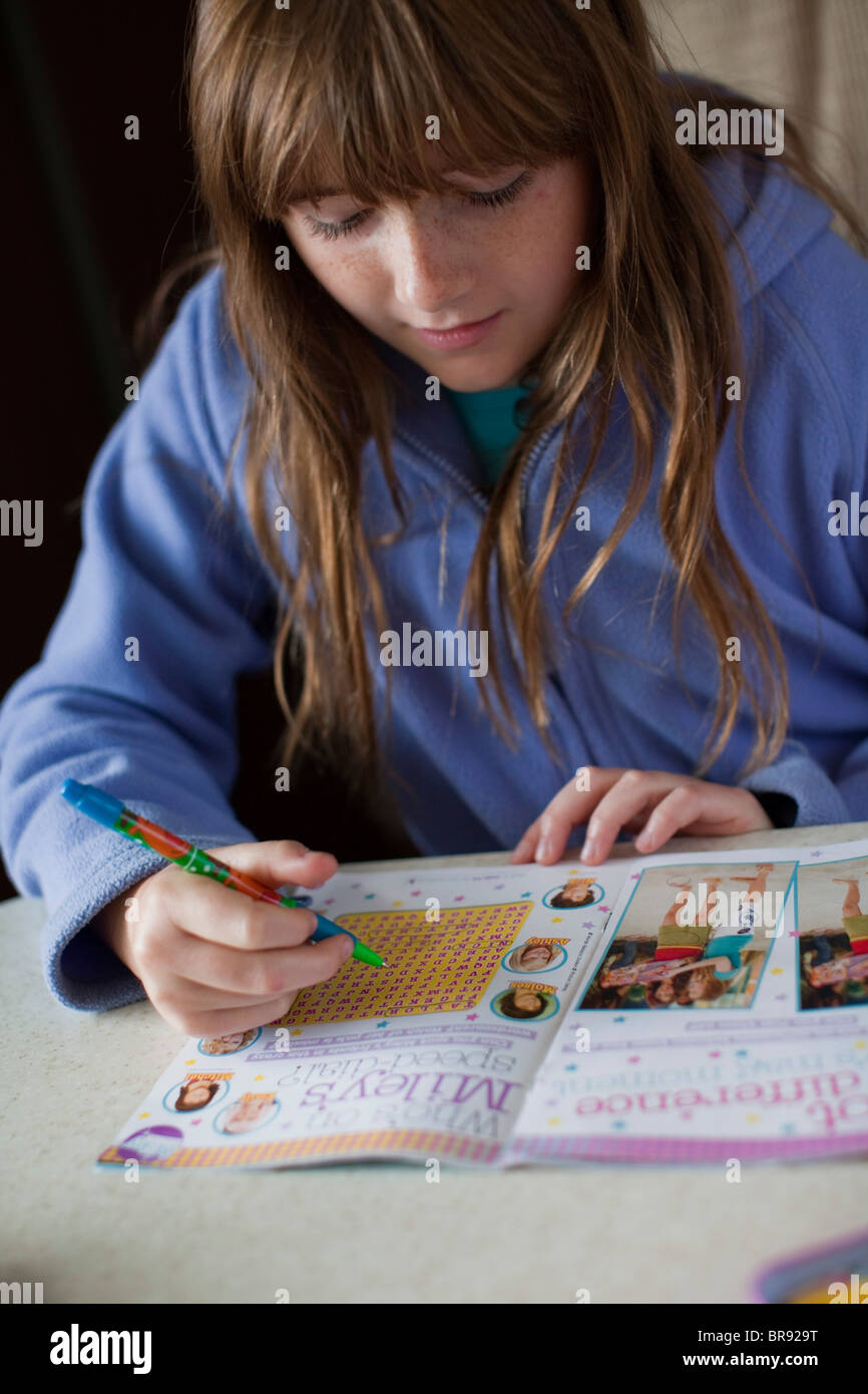 Ragazza adolescente facendo un puzzle libro mentre era in vacanza in una roulotte nel Regno Unito Foto Stock