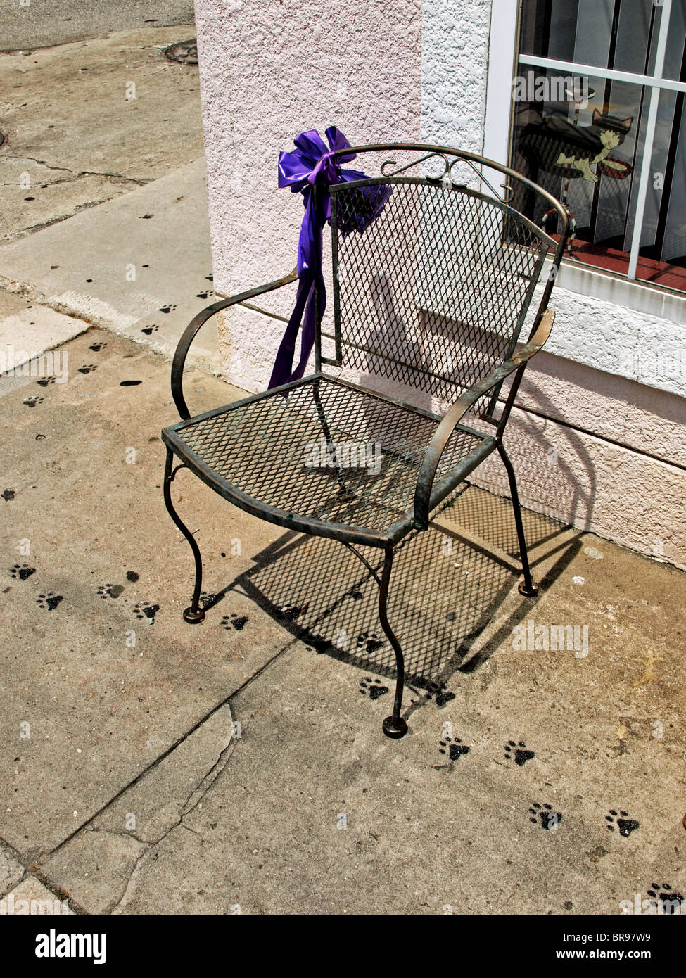 Il filo esterno della sedia in metallo con nastro viola sul bordo seduti davanti ad una rosa edificio in stucco Foto Stock