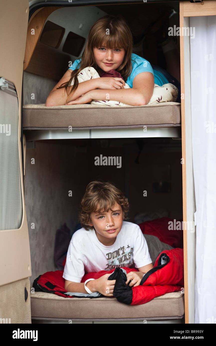 Un ragazzo e una ragazza che giace su letti a castello in una traversina van. Foto Stock
