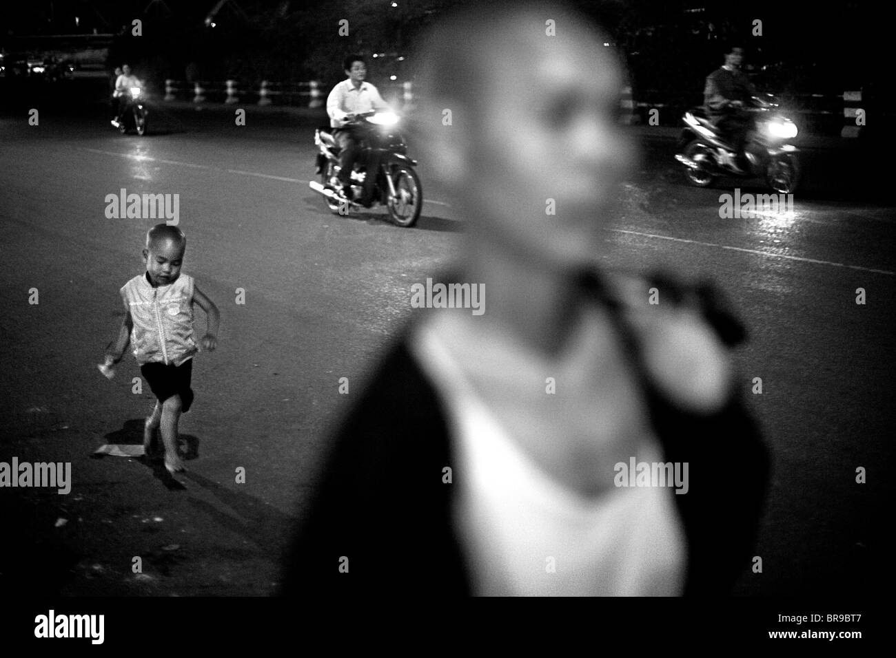 Figlio corre per la cattura di madre in strada di Hanoi, Vietnam. Foto Stock