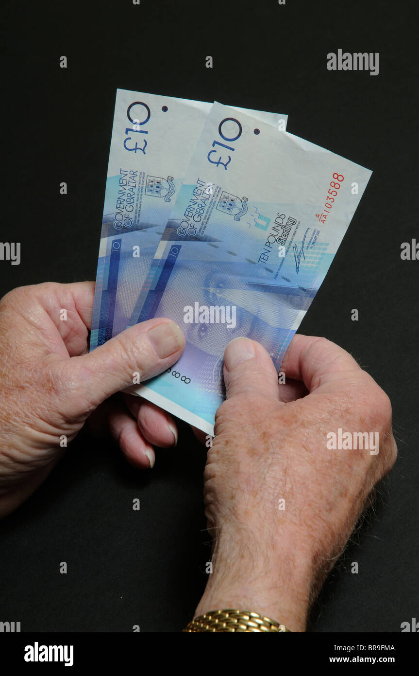 Uomo anziano le mani tenendo il governo di Gibilterra dieci pound note Foto Stock