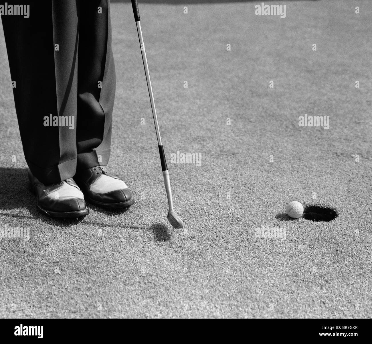 Anni Cinquanta l uomo le ginocchia verso il basso putt golf sul green Foto Stock