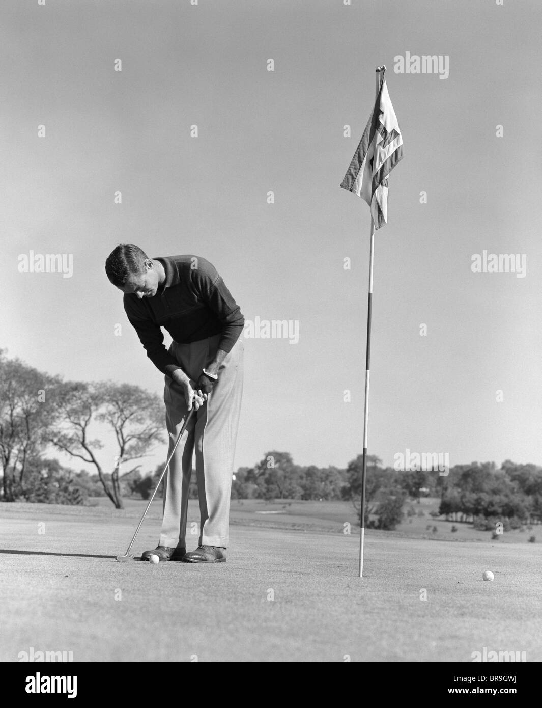 Anni Cinquanta anni sessanta uomo golfista mettendo su verde Foto Stock
